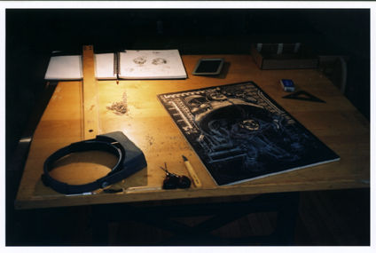 A close-up of Robert's desk. A half completed print sits on the desk.